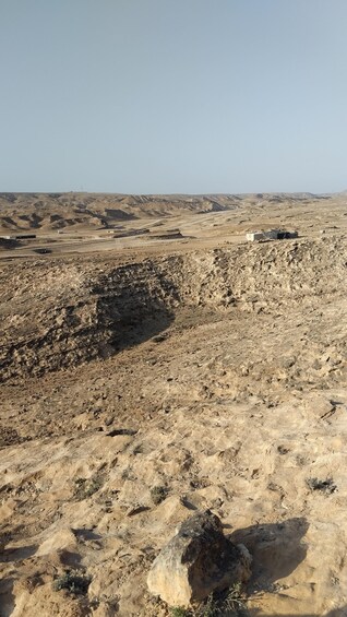 A barren desert landscape with rocky terrain and sparse vegetation. 5