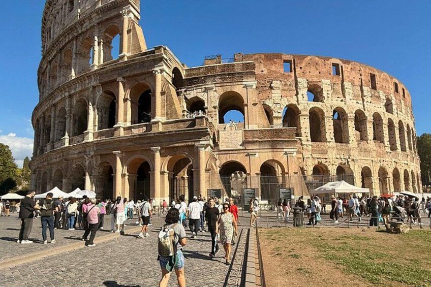 The Colosseum with tourists walking around. 3