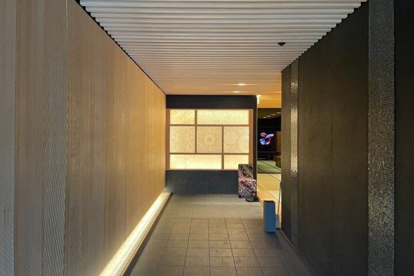 A corridor with a patterned ceiling, a large window, and a seating area with a colorful chair. 4