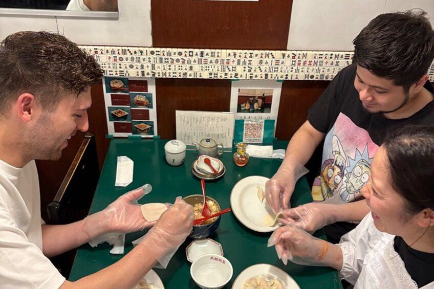 Three people preparing food at a table with bowls, chopsticks, and a spoon. 3