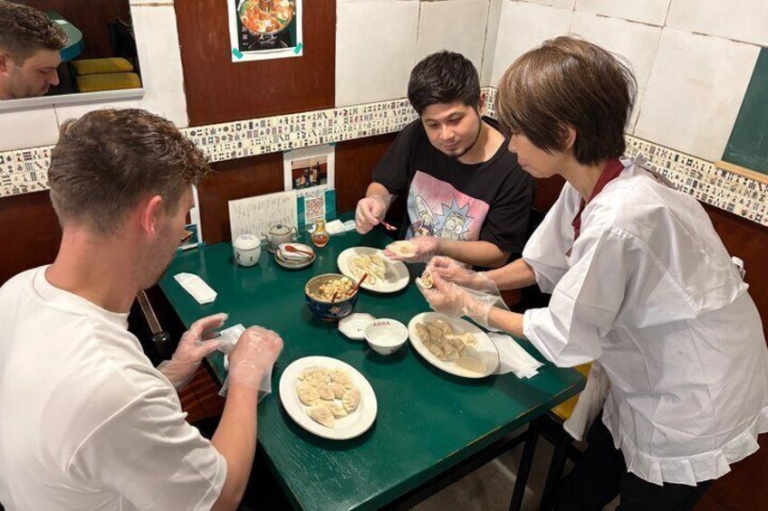 A group of people dining at a restaurant with a green table and tiled walls. 1