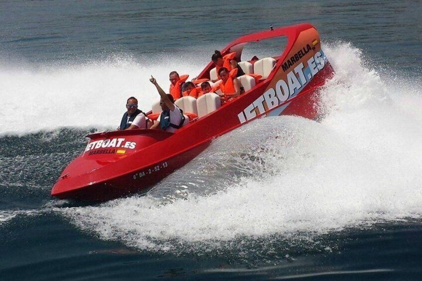 A red speedboat with passengers, labeled 'IETBOATES,' moving through water. 2