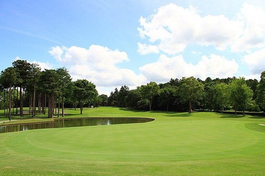 En golfbana med en damm, träd och en klar himmel. 5