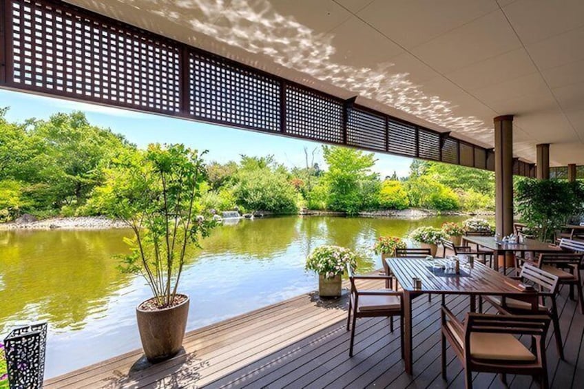 A wooden deck overlooking a calm river, surrounded by lush greenery and potted plants. 4