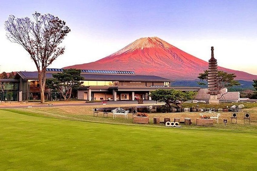 A grassy area with a pagoda, a building, and a mountain in the background. 1