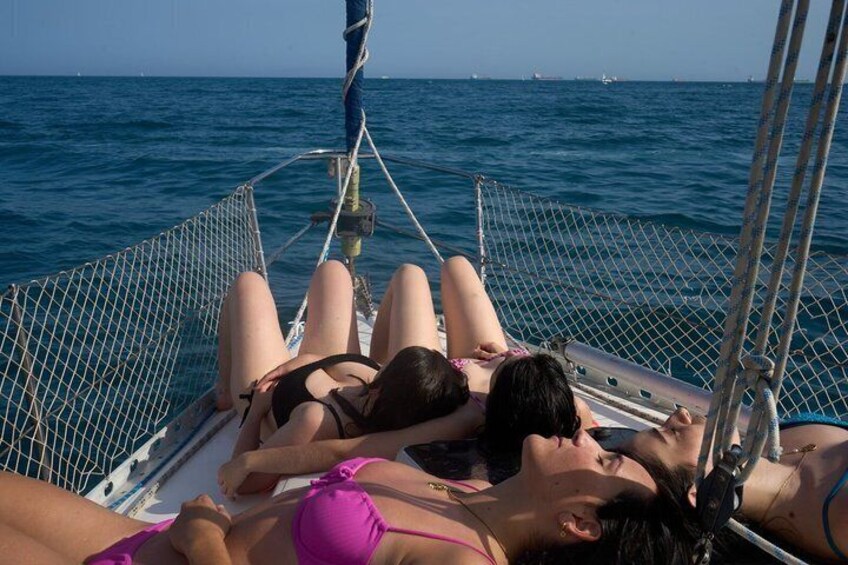 Three people lying on a boat deck with the ocean in the background. 2