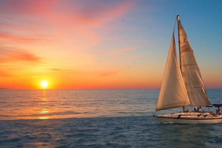 A sailboat with two sails on calm waters at sunset. 4