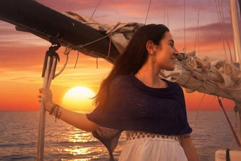 A person on a sailboat with the sun setting in the background. 3