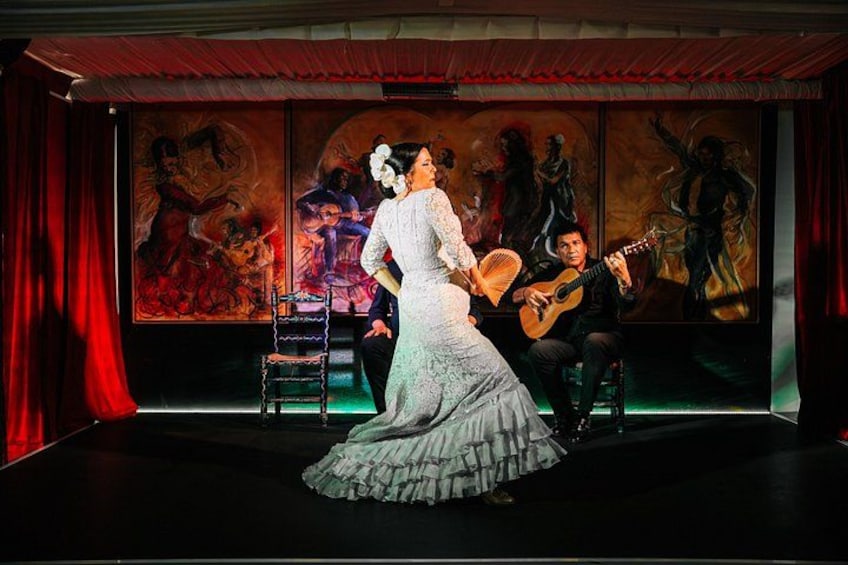 A person in a white dress on a stage with a guitar player. 2