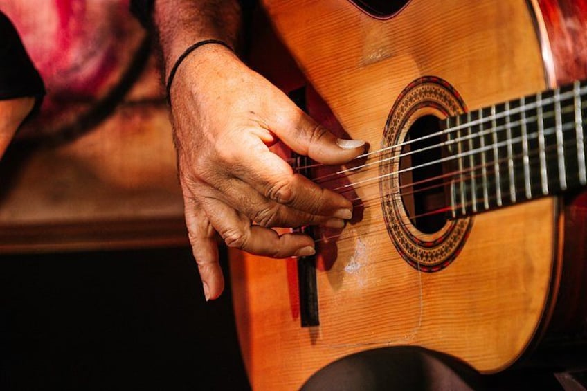 A person's hands playing an acoustic guitar. 3