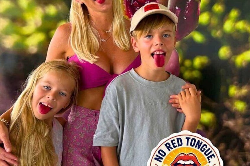 A woman in a pink top and a child in a grey shirt holding a sign with a red tongue graphic. 1