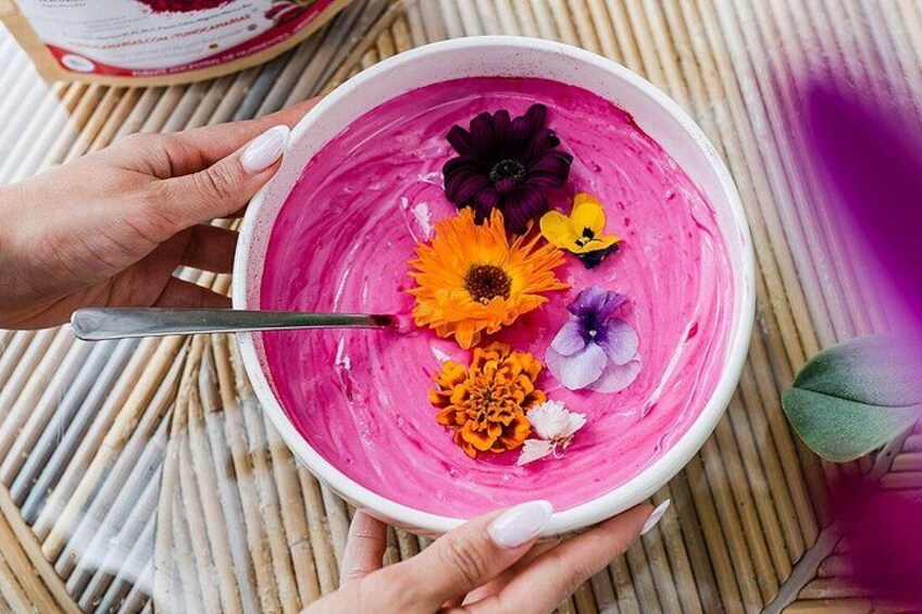 A bowl of pink smoothie with various flowers on top. 4