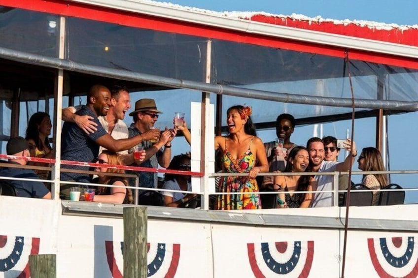 A group of people on a boat with a red and white striped awning, some holding drinks. 5