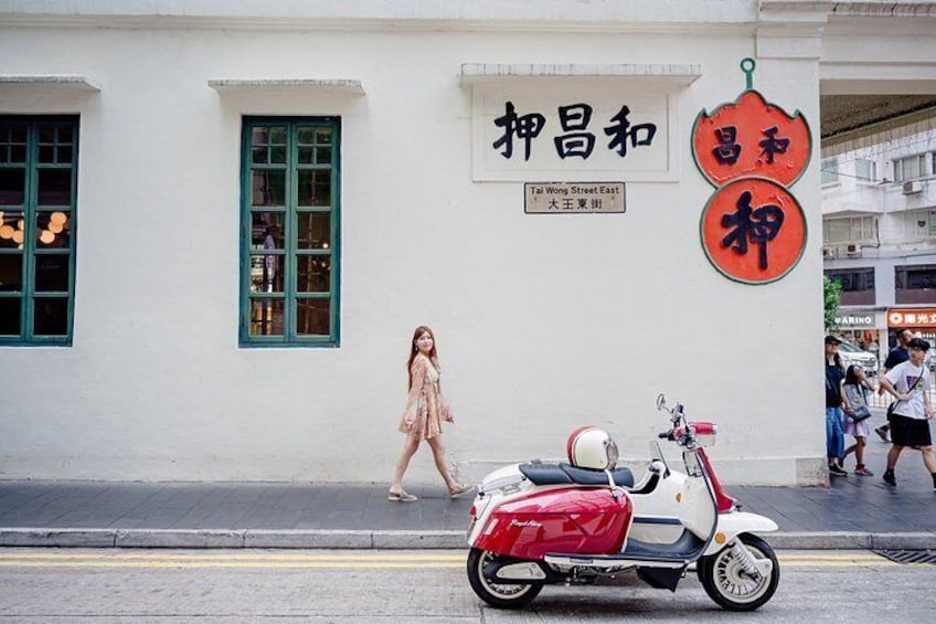 A street scene with a white building, a red scooter, and a pedestrian. 4