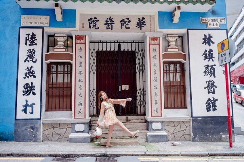 A woman in a dress standing in front of a building with Chinese characters on the facade. 5