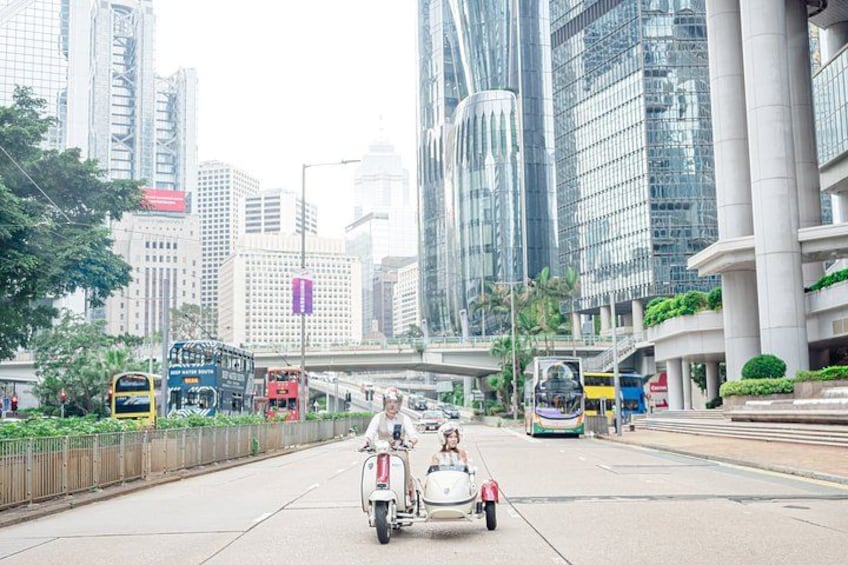 A city street with modern buildings, a pedestrian bridge, and a motorcycle with a sidecar. 3