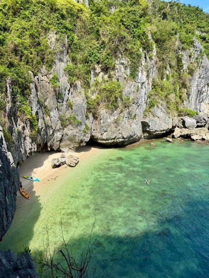 A coastal landscape with clear turquoise waters, rocky cliffs, and a sandy beach. 2