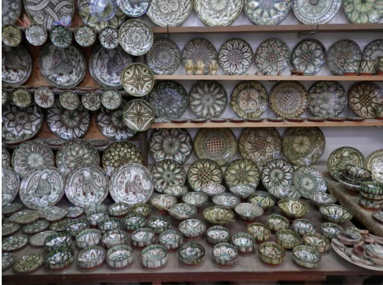 A variety of intricately designed ceramic plates and bowls on shelves. 4