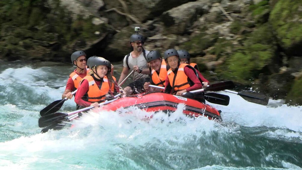 A group of people in a red raft navigating through a river with rapids. 2