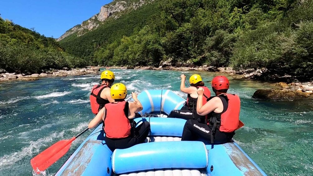 A group of people rafting on a river surrounded by greenery. 3