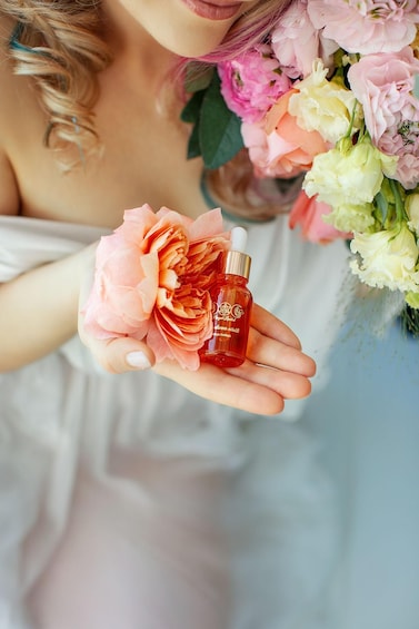 A person holding a pink flower and a small bottle. 4
