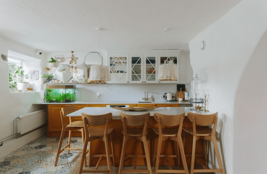 A kitchen with wooden chairs, a fish tank, and white cabinets. 5