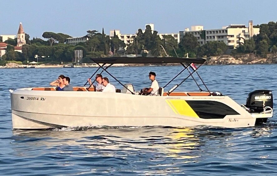 A white motorboat with a yellow stripe on the side, labeled '269514 RV,' on calm water with a cityscape in the background. 2