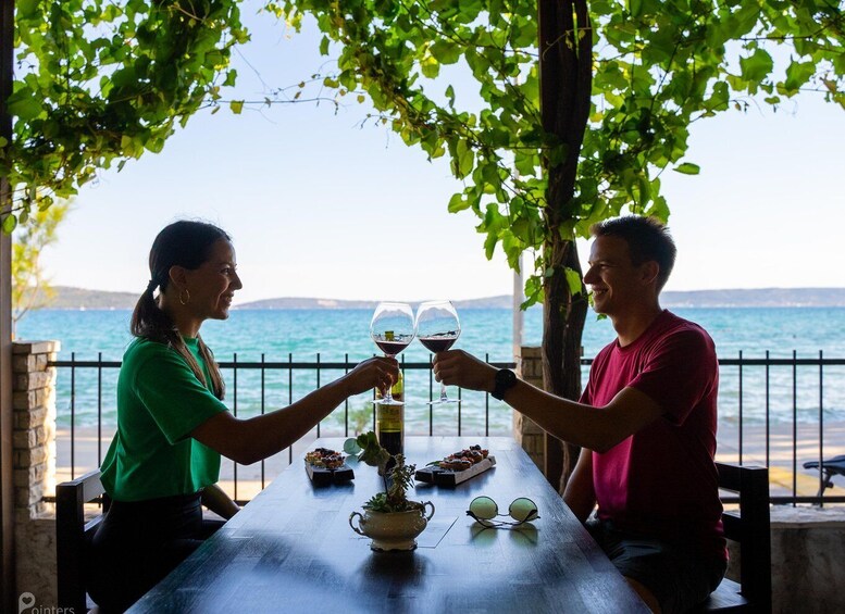 Two people toasting with wine glasses at a table with a view of the sea. 3