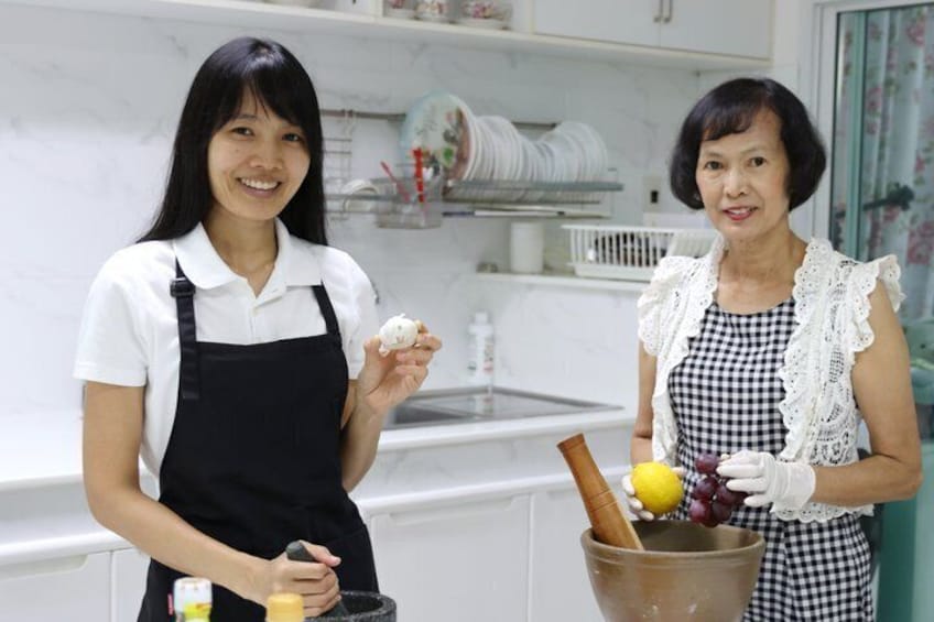Two individuals in a kitchen holding food items and a bucket with fruits and a wooden spoon. 1