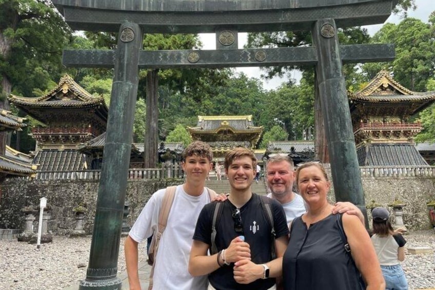 A group of people standing in front of a traditional Japanese torii gate with a temple in the background. 4