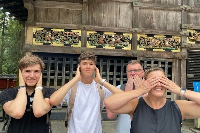 A group of people standing in front of a wooden building with intricate carvings. 5
