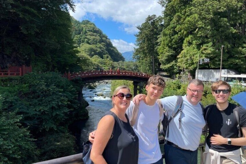 A group of people standing by a river with a bridge in the background. 5