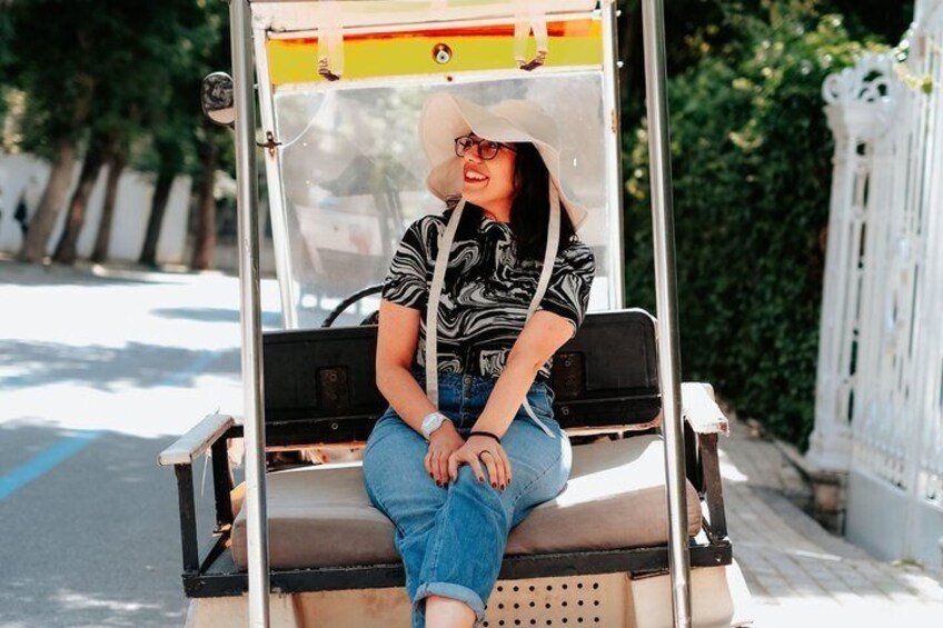 A person sitting on a golf cart with a bag on the back. 2