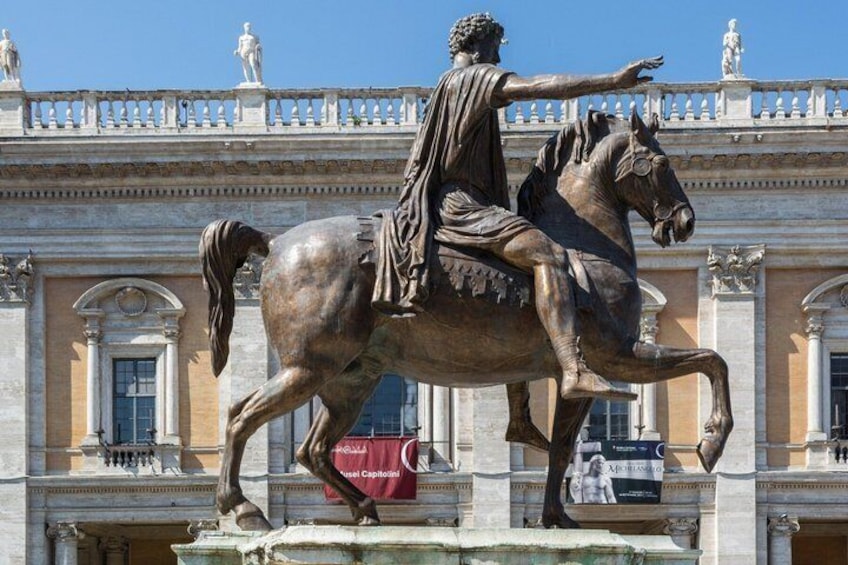 A bronze statue of a man on horseback in front of a classical building with columns and statues. 4