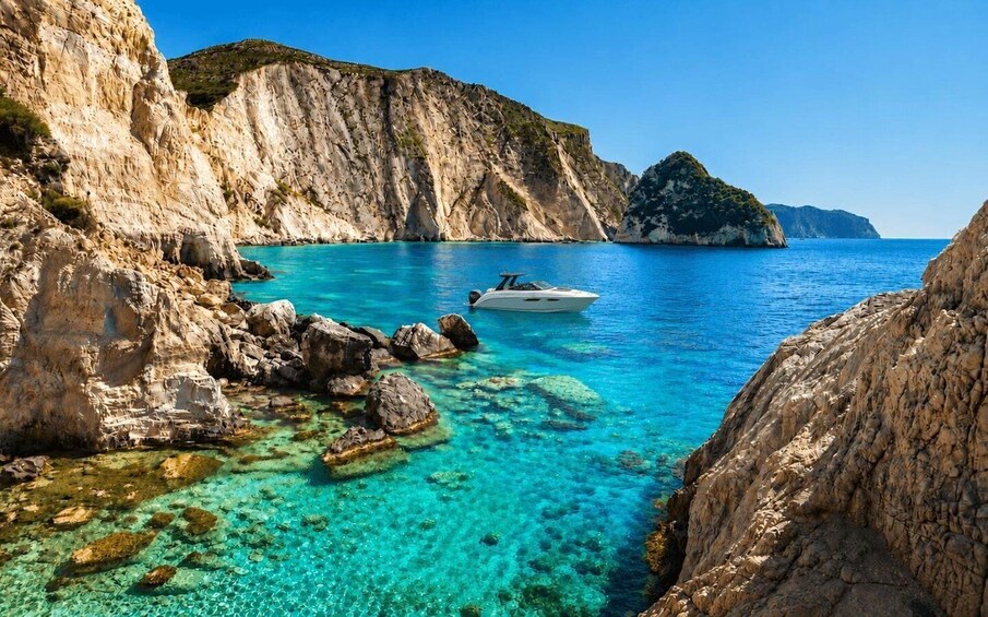 A boat anchored near rocky cliffs with clear turquoise water. 1