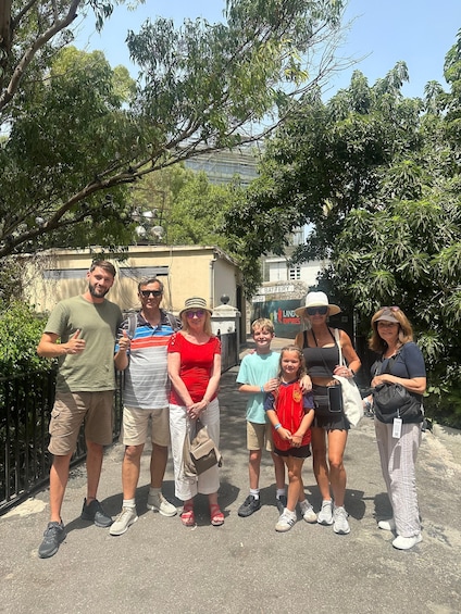 A group of people standing outdoors with trees and a building in the background. 3