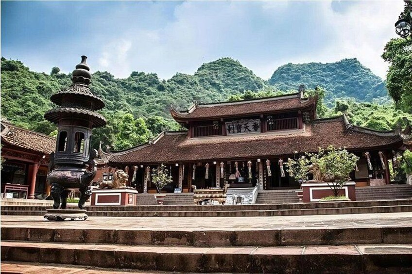 A traditional Chinese building with a pagoda-like structure in front, surrounded by lush greenery and hills. 5
