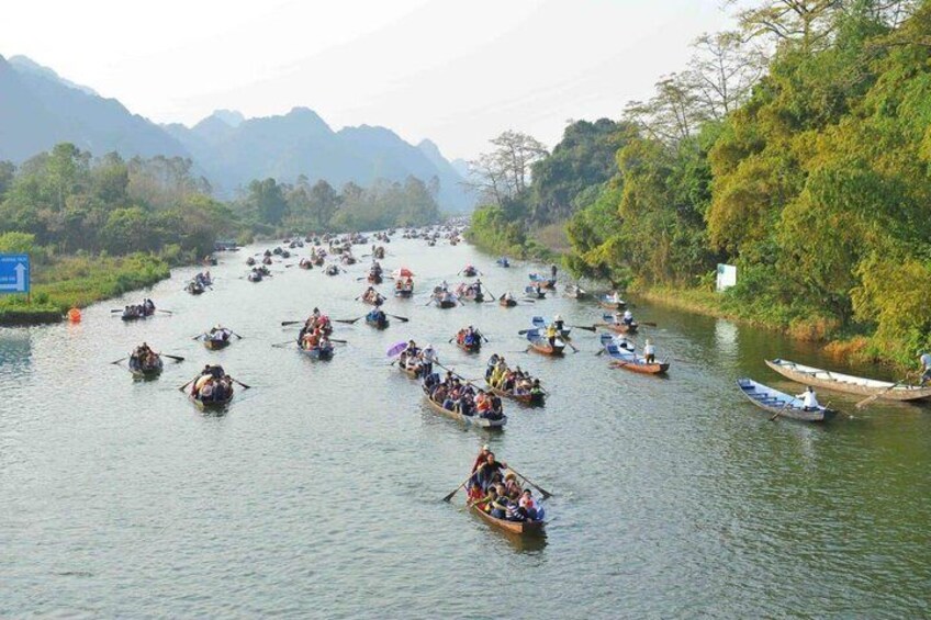 A river with multiple boats, dense greenery, and distant mountains. 4