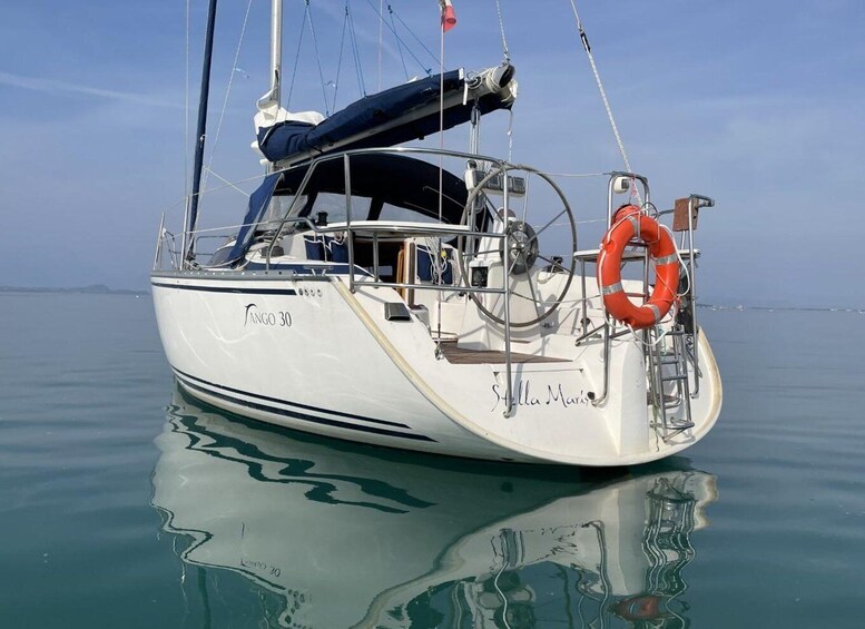 A white sailboat named Tango 30 with a blue cabin and a life ring on the bow. 2