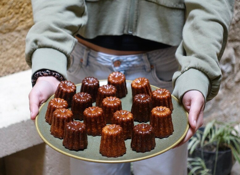 A person holding a plate of caramelized desserts. 5