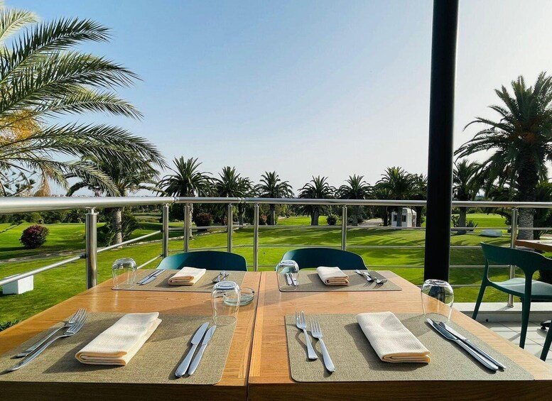 A table set outdoors with a view of a well-manicured lawn and palm trees. 3