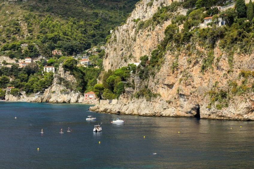 A coastal landscape with rocky cliffs, a clear blue sea, and boats. 4