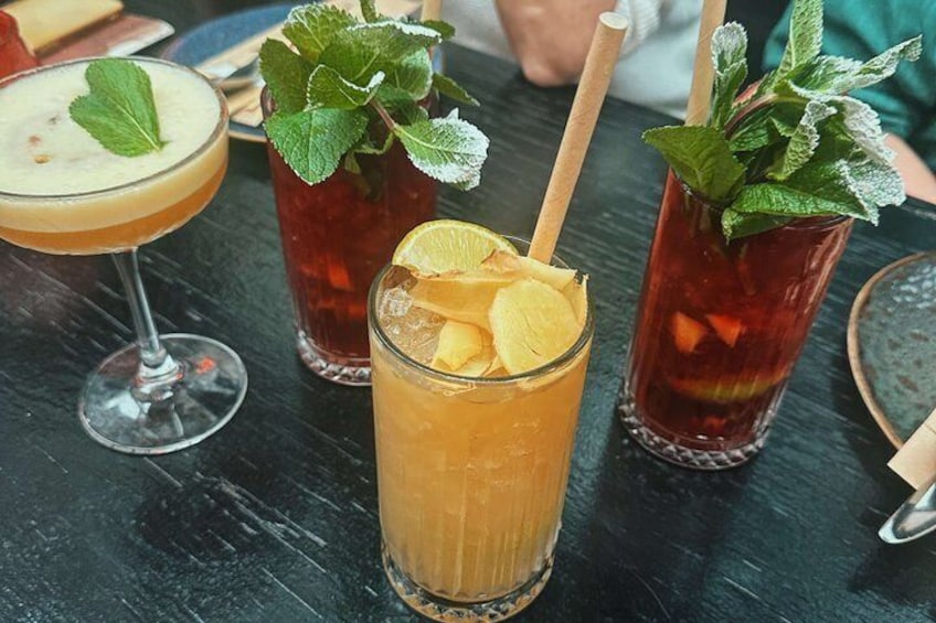 Three drinks with mint leaves and lemon slices on a wooden table. 5