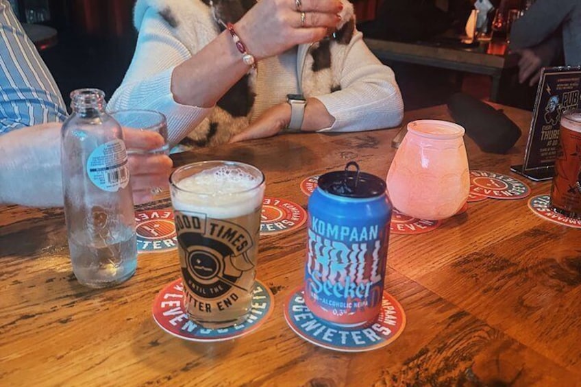 A wooden table with a glass of beer, a can of beer, and a bottle of water. 2
