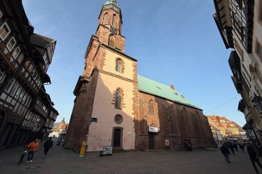 A historic church with a prominent tower and a green roof, surrounded by traditional half-timbered buildings. 5