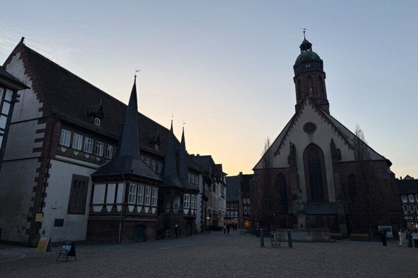 A historic town square with traditional half-timbered buildings and a church with a prominent tower. 3