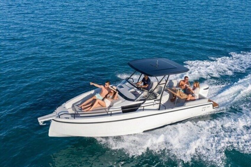 A white motorboat with a canopy, people on board, and a wake in the water. 1