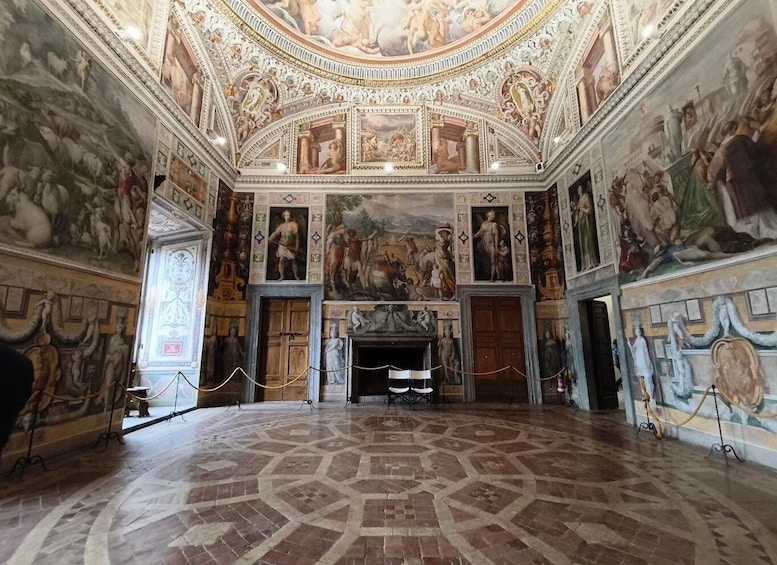 An ornate room with detailed frescoes and a geometric patterned floor. 4