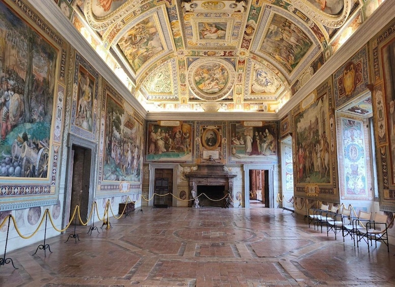 An ornate room with frescoes, a fireplace, and classical architecture. 5