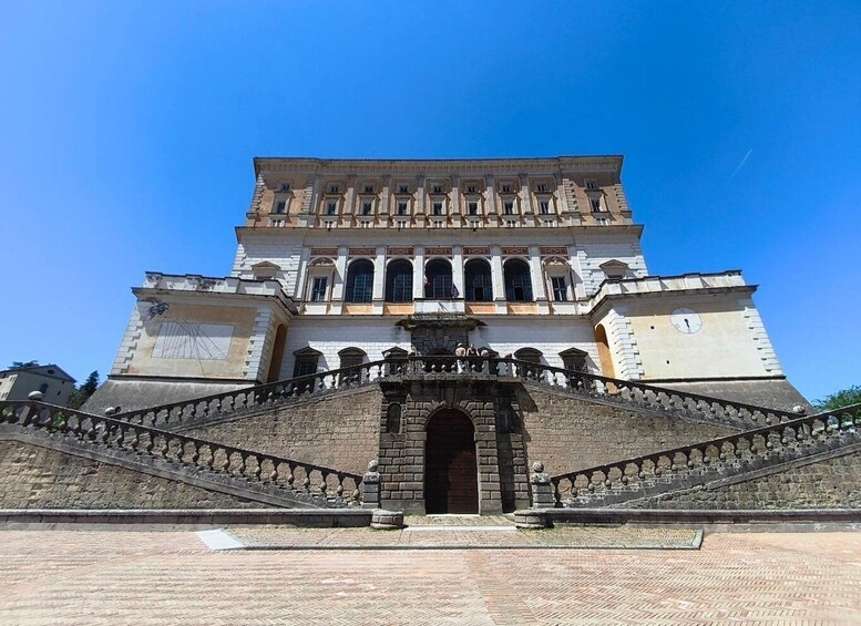 A large, historic building with a central archway and a staircase leading up to it. 3